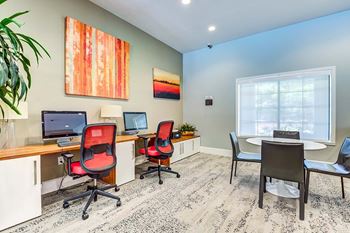 A room with a desk, chairs, and a computer.